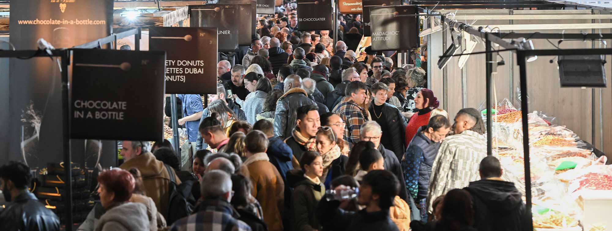 Gros plan sur une allée du Salon du Chocolat de Lyon avec ses visiteurs. 