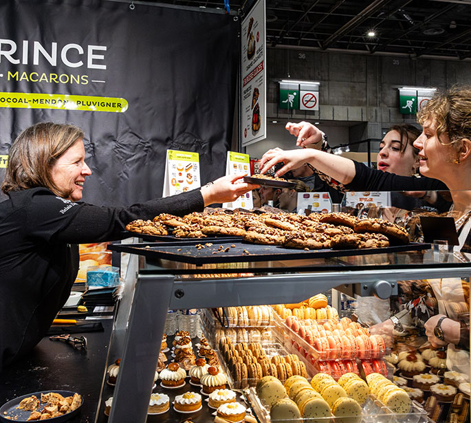 Stand animé au Salon du Chocolat avec des visiteurs découvrant des créations chocolatées. 