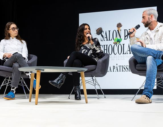 Conférenciers s'adressant à un public lors d'une table ronde sur l'industrie du chocolat.