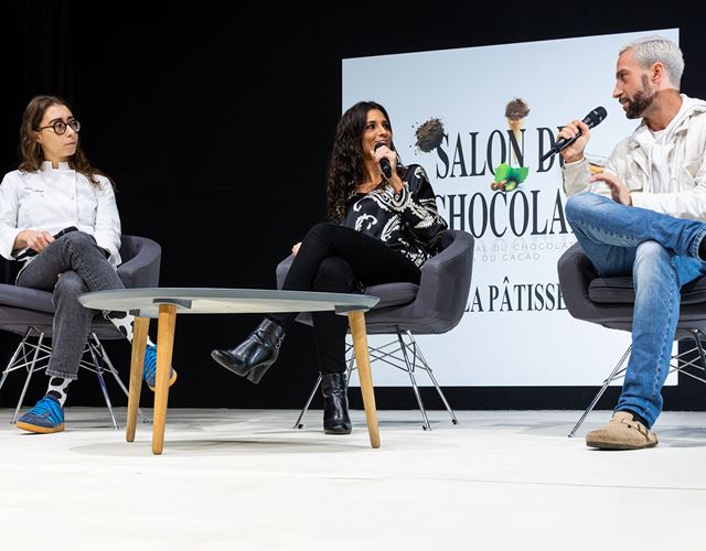 Conférenciers s'adressant à un public lors d'une table ronde sur l'industrie du chocolat.