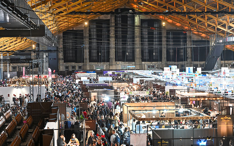 Vue panoramique du Salon du Chocolat de Lyon à la Halle Tony Garnier avec de nombreux stands et visiteurs.