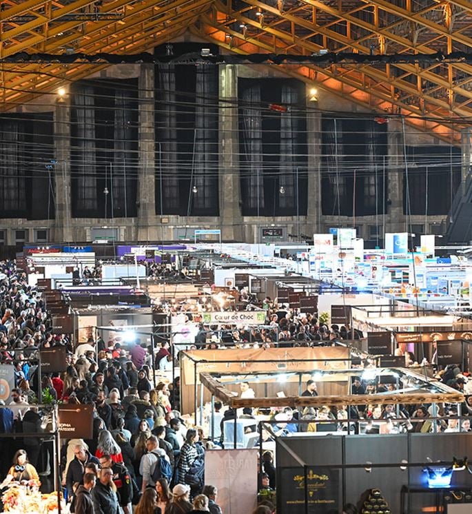 Panoramic view of the Salon du Chocolat de Lyon at the Halle Tony Garnier with numerous stands and visitors.