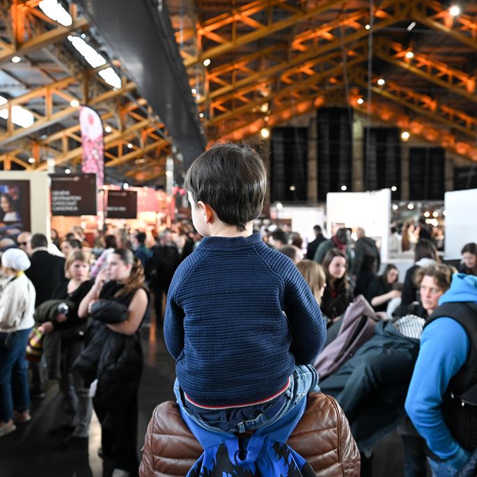 Petit garçon sur les épaules de son papa dans les allées du Salon du Chocolat