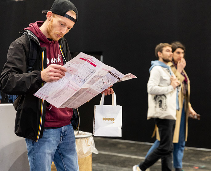 Quelqu'un qui regarde le plan dépliable du Salon du Chocolat de Lyon.