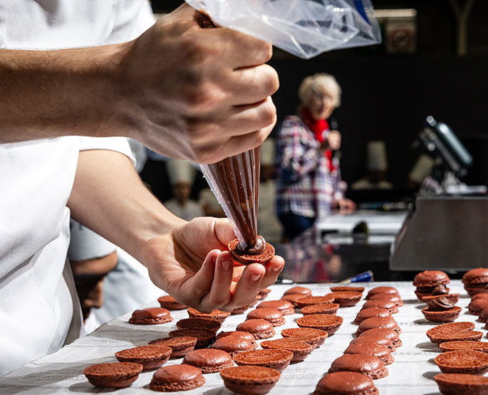 Geste pâtissier d'un chef en pleine démonstration live.