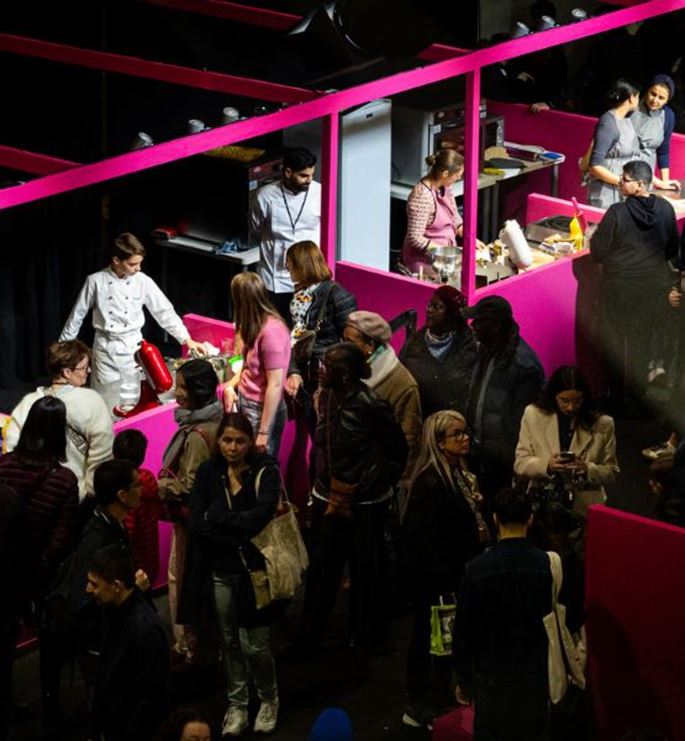 Atelier gastronomique interactif avec chefs et visiteurs participant à des démonstrations culinaires dans un stand coloré au salon