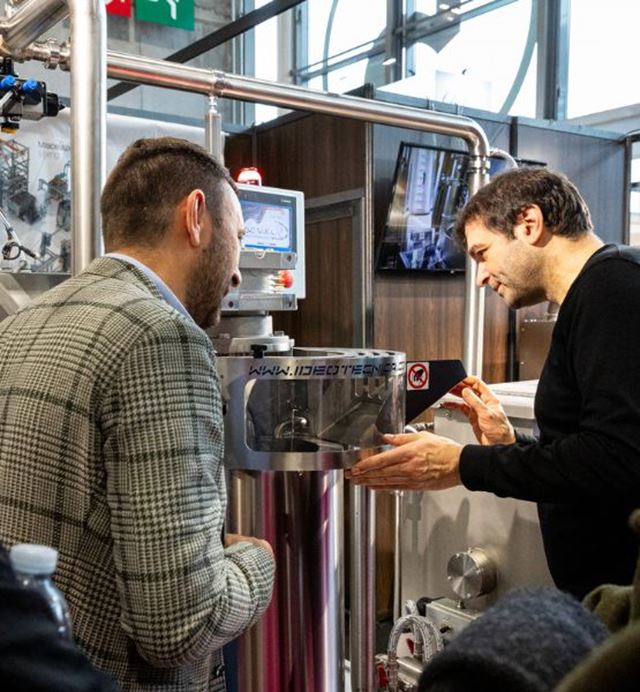 Démonstration d’une machine industrielle avec deux professionnels observant un équipement technologique sur un salon