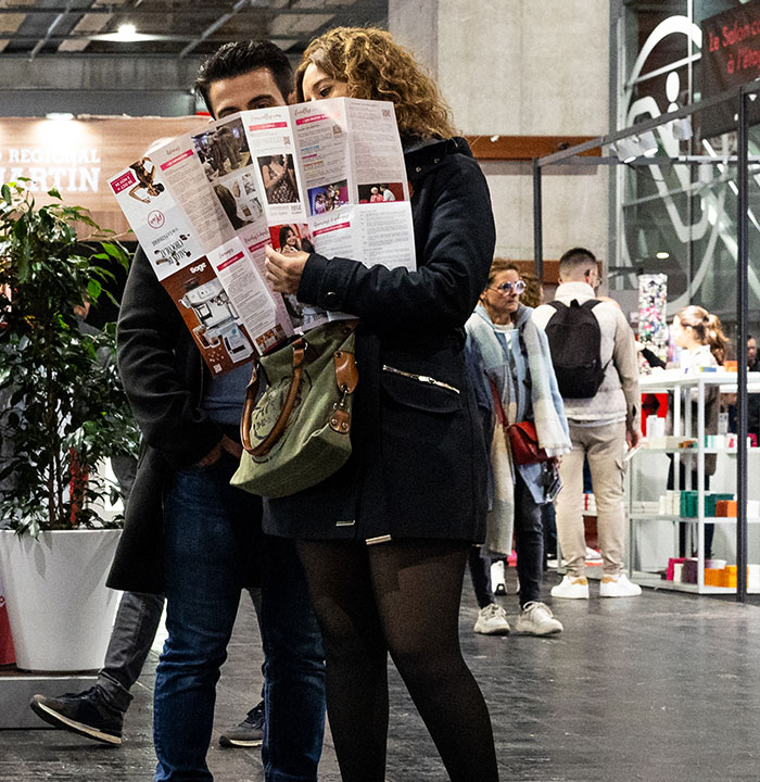 Duo de visiteurs en train de regarder le plan dépliable du Salon du Chocolat. 