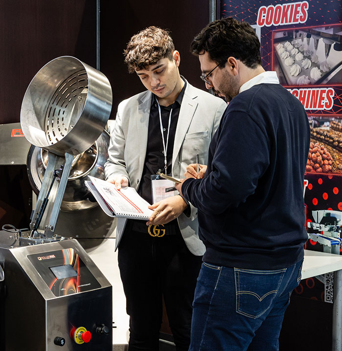 Discussion entre deux professionnels autour d'une machine sur le Village B2B. 